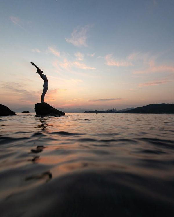 Silhouette of a person in a stretching yoga pose during a peaceful sunset.